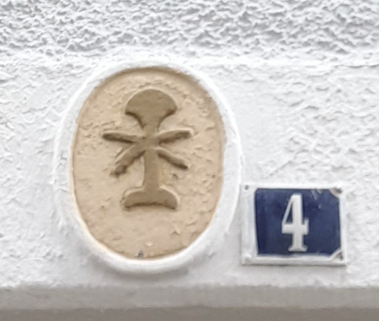 Fotografiertes Gerber-Zunftzeichen neben Hausnummer 4 in der Mühlgasse in Lahr mit Scherbaum und gekreuzten Schabeisen